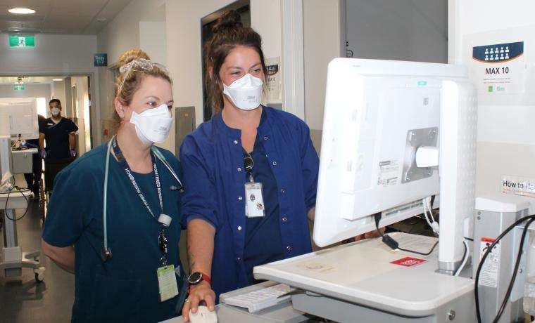 Emergency Department Associate Nurse Unit Manager Alyssa Hughes (right) discusses a case with Registered Nurse Carli Johnstone.