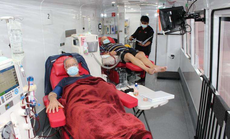 Patients John Sevastopoulos, front, and John Casey, receive haemodialysis treatment in the Big Red Kidney Bus from Registered Nurse Julee Rajesh.
