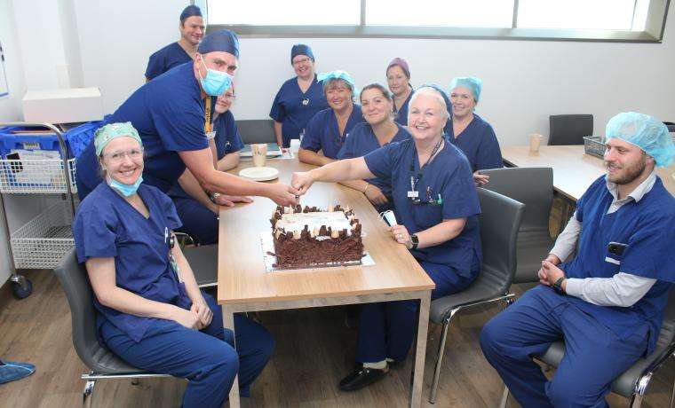 Bass Coast Health’s Perioperative Nurse Unit Manager Carol Cruickshanks cuts a cake celebrating the completion of new Theatres, joined by BCH staff.