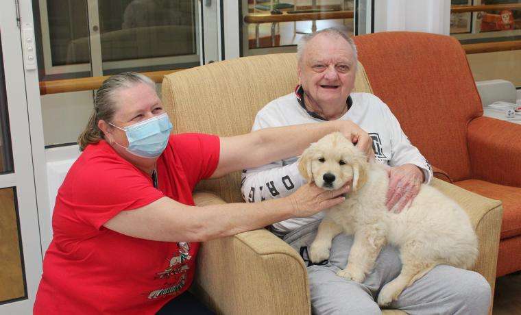 Max the Golden Retriever shares a moment with Kirrak House resident Graham Neason and Diversional Therapist Gai West.
