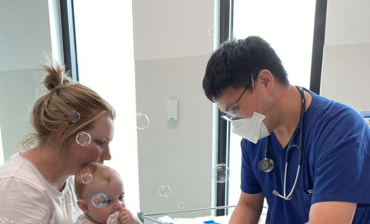 Patient Fletcher Wilson is entertained by bubbles, seemingly unaware of being treated by Dr Caleb Lin  at the Urgent Care Centre at Cowes while his mother Hannah Wilson watches on.
