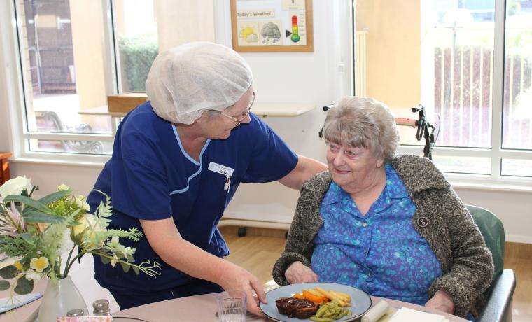 Kaye Henshall, a member of the Food Services team at Kirrak House, Wonthaggi, serves lunch to  resident Jean Smith, with a smile.