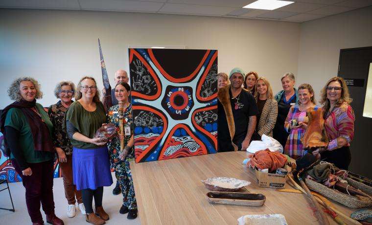 Phillip Island Community Hospital staff display the artwork they made with First Nations artist Steve Parker, right of painting.